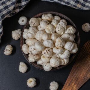 A rustic bowl filled with puffed lotus seeds on a black background, perfect for snacks.